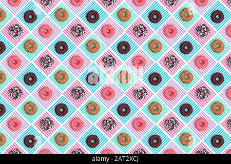 Pattern of pink, white and chocolate donuts on multi-colored striped background top view, tasty doughnuts backdrop, colorful wallpaper Stock Photo