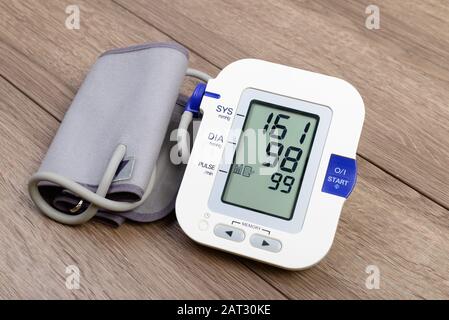 White automatic blood pressure monitor (tonometer) on wooden table Stock Photo