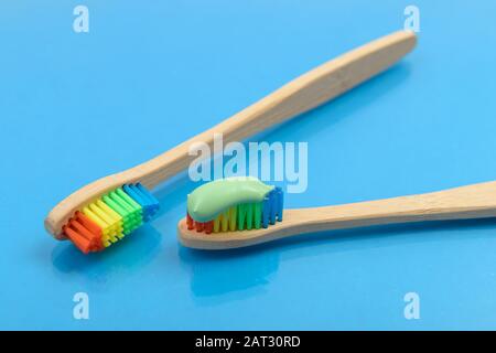 Bamboo toothbrush with green toothpaste on blue background with water drops. Eco friendly concept Stock Photo