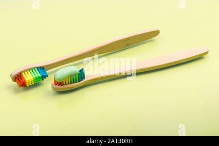 Bamboo toothbrush with eco green toothpaste on pastel background. Pair of multi-colored wooden tooth brushes Stock Photo