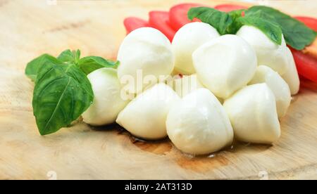 Mozzarella cheese with tomatoes and basil on wooden desk Stock Photo