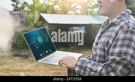 Agriculture technology attractive farmer navigating farmland with laptop computer  innovations for increasing productivity in agriculture. Stock Photo