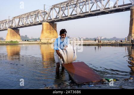 Uttar Pradesh, India - March 03, 2018: Unidentified man doing a laundry at Dhobi Ghat is a well known open air laundromat in Yamuna River, Agra. Stock Photo