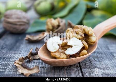 Walnuts and walnut kernels lie in a spoon on a rustic old wooden table. Kernels of walnuts. Harvest walnuts. Stock Photo
