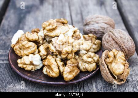 Walnut kernels lie in a bowl on a rustic old wooden table. Fresh walnuts. Harvest walnuts. Stock Photo