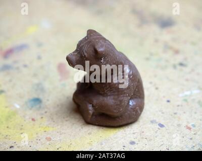 A brown chocolate-colored bear sits on wooden surface. Side view Stock Photo