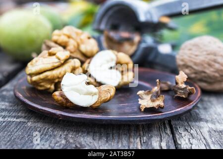 Walnuts and walnut kernels lie on a bowl on a rustic old wooden table. Walnut kernels. Harvest walnuts. Stock Photo