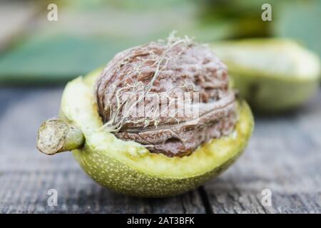 Fresh walnuts in a green shell on an old wooden table. Nuts in green shells. Harvest walnuts. Stock Photo