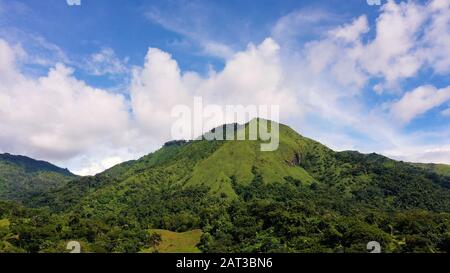 Hills with green grass and blue sky with white puffy clouds. Beautiful landscape on the island of Luzon, aerial view. Stock Photo