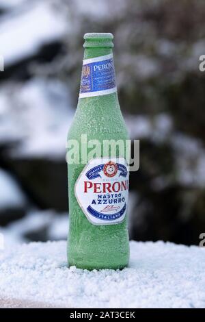 Frozen Peroni beer bottle on a cold winter day in Kuopio, Finland November 2019. The bottle says blue ribbon, superior quality from Italy in Italian. Stock Photo