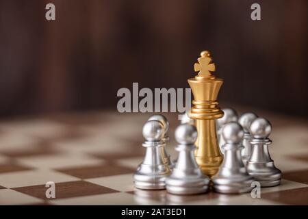 gold king standing in the midst of chess on board Stock Photo