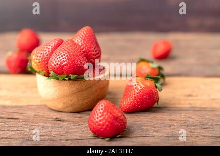 Freshness ripe strawberries are in a wooden bowl placed on the table. Stock Photo