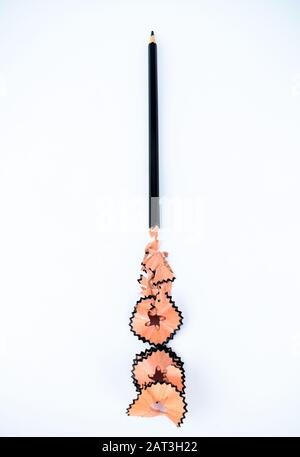 Black wood pencil with some pencil shavings is showing on an isolated white background Stock Photo
