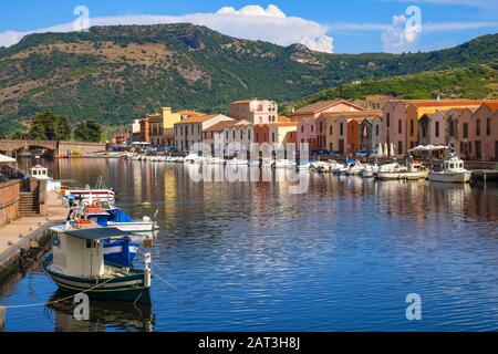 Bosa, Sardinia / Italy - 2018/08/13: Panoramic view of the old town quarter of Bosa by the Temo river embankment with colorful tenement houses and boats Stock Photo