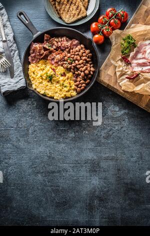 English breakfast scrambled eggs grilled bacon beans and toast bread - Top of view Stock Photo