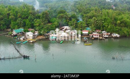 Fishing village with wooden houses standing on stilts in the sea from above. Houses community standing in water in fishing village. Luzon, Philippines. Stock Photo