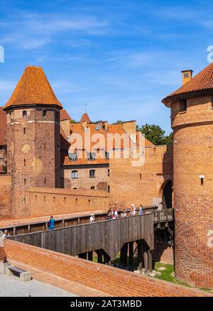 Malbork, Pomerania / Poland - 2019/08/24: Panoramic view of the medieval Teutonic Order Castle in Malbork, Poland - external defense walls with lower castle gate tower and drawbridge over the moat Stock Photo