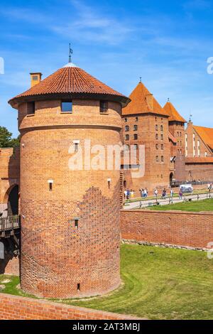 Malbork, Pomerania / Poland - 2019/08/24: Panoramic view of the medieval Teutonic Order Castle in Malbork, Poland - external defense walls with lower castle gate tower and drawbridge over the moat Stock Photo