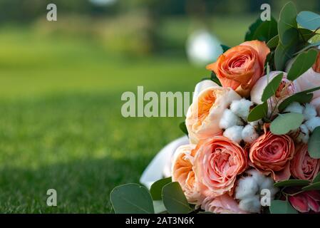 A wonderful colored bouquet of roses lies on the grass, a place for text .- Image Stock Photo