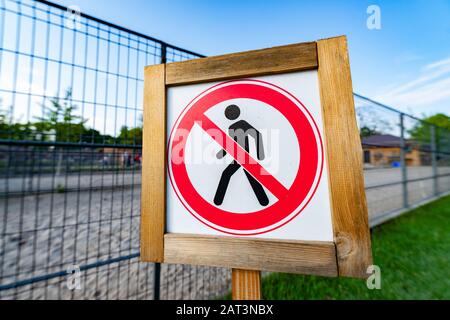 Prohibition No Pedestrian Sign next the fence.  Prohibited signs figura of walking man in a crossed circle isolated on white background. Stock Photo