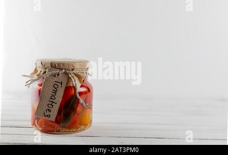 glass jar of fermented tomato. vegetables on a light background. fermentation is a source of probiotic Stock Photo