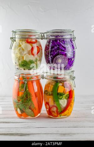 glass jars of fermented red cabbage, cauliflower, cucumbers, onions, carrots, vegetables on a light background. fermentation is a source of probiotics Stock Photo