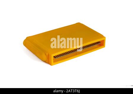 TV game cartridge in plastic yellow case from 90s. Yellow game cartridge with a set of games on a white background. Close-up. Selective focus. Stock Photo
