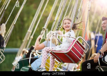 Little girl having fun on chain carousel. Happy summer memories. Carefree childhood and happiness Stock Photo