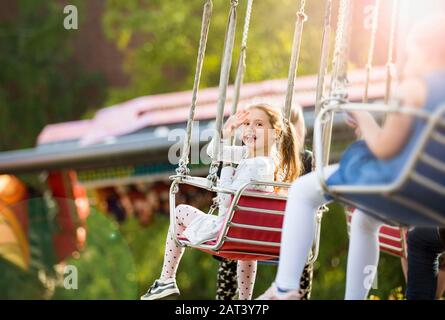 Little girl having fun on chain carousel. Happy summer memories. Carefree childhood and happiness Stock Photo