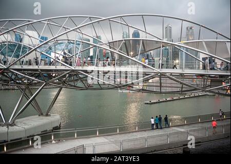 26.01.2020, Singapore, Republic of Singapore, Asia - People cross Helix Bridge in Marina Bay with skyscrapers of central business district in backdrop. Stock Photo