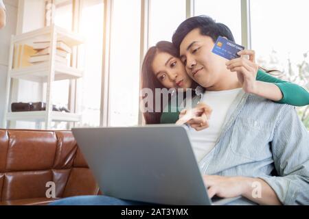 Couples help each other online shopping with credit cards. Stock Photo