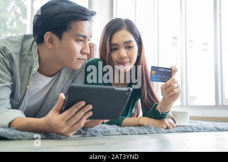 Couples help each other online shopping with credit cards. Stock Photo