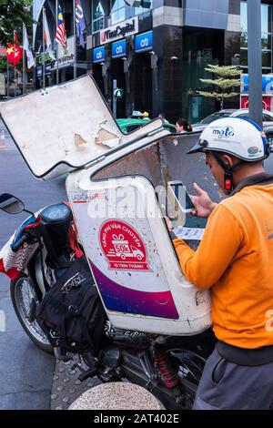 Man checks delivery of a packet on his mobile phone, Ho Chi Minh City, Vietnam Stock Photo