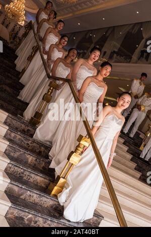 Young women in long white dress on the stairs await bride & groom for wedding reception, Ho Chi Minh City,Vietnam Stock Photo
