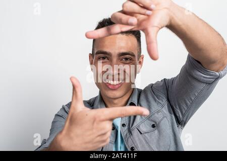 Closeup smiling face of mulatto man in the square from gesture with male  fingers.- Image Stock Photo