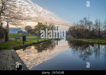 Picturesque, urban landscape view of English town, Kidderminster, UK, early winter morning. Dramatic clouds in blue sky reflected in still canal water. Stock Photo