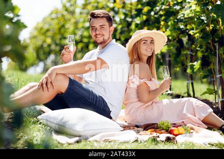 Beautiful girl in hat and young man relaxing in the vineyard Stock Photo