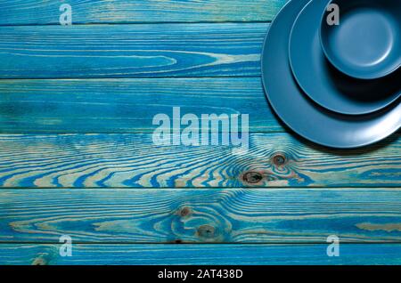Colored plates of different shapes stand on a wooden background. Stock Photo