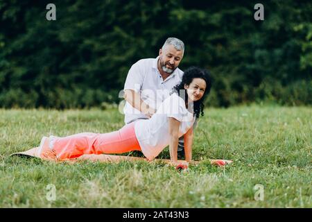 Middle age woman  doing yoga. Man help for woman with exercise.-  - Image Stock Photo