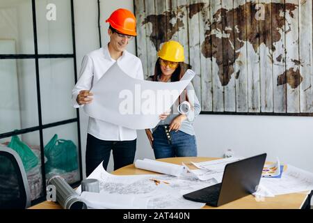 Architects in helmets looks at blueprint in office Stock Photo