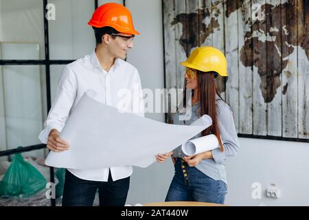 Young architects colleagues are analyzing blueprints while working on a new project in the office. Stock Photo