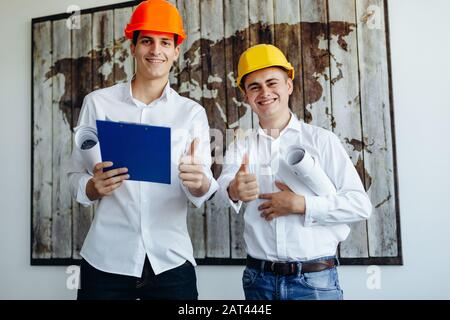 Two young engineers in construction helmets with a tablet and blueprints Stock Photo