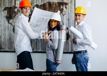 Smiling young engineers working on blueprints in the office Stock Photo