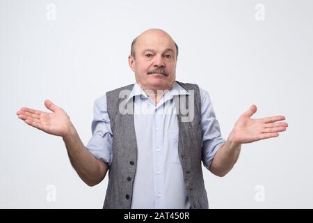 Clueless doubtful displeased senior man shrug shoulders in uncertainty, does not know how change future life or what to do. Studio photo. Stock Photo