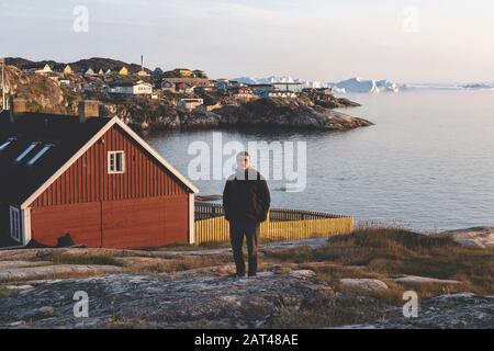 Travel in arctic landscape nature with icebergs. Greenland tourist man explorer. tourist person looking at amazing view of Greenland icefjord. Man by Stock Photo