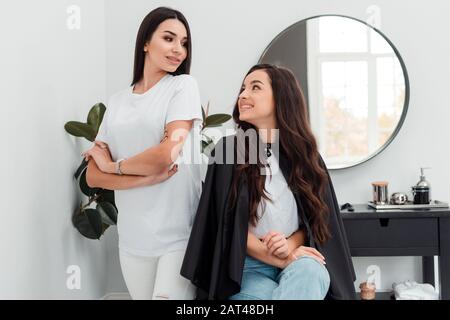 Young beautiful woman discussing hairstyling with her hairdresser while sitting in the hair salon Stock Photo