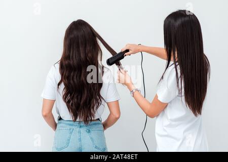 Professional hairdresser straightens the client's hair Stock Photo