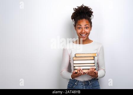 Portrait of an excited young girl holding books over white background. Back to school Stock Photo