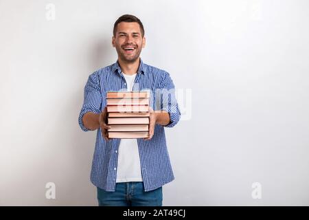 Portrait of happy young man holding books in his straight hands. Back to school Stock Photo