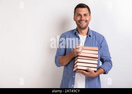 Portrait of happy nerd young man holding books in his hands. Back to school Stock Photo
